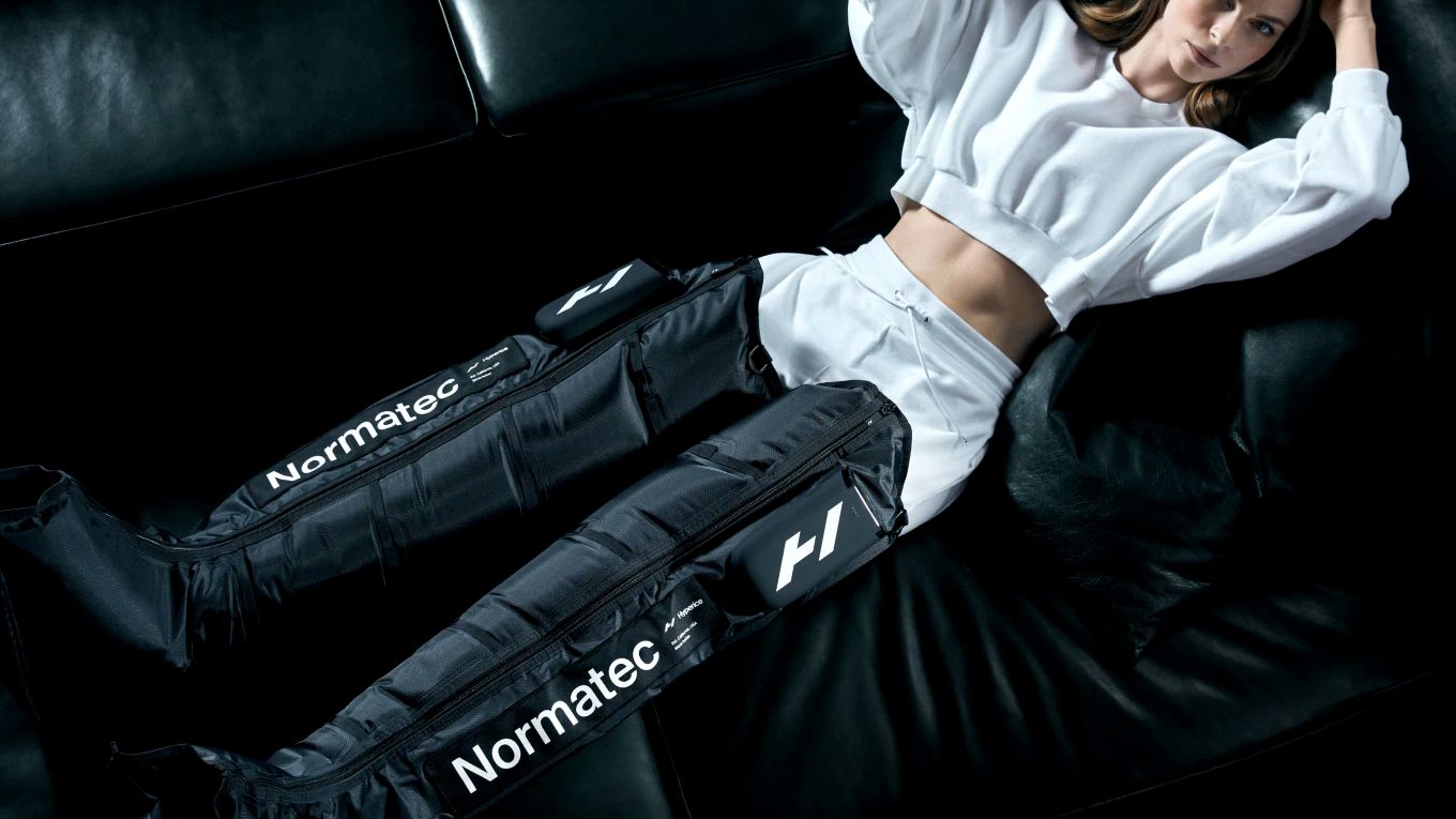 A person resting back with NormaTec compression boots on both legs