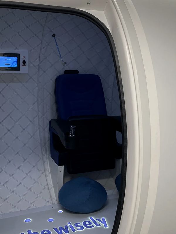 The open door of the hyperbaric chamber, showing the seat and control panel inside