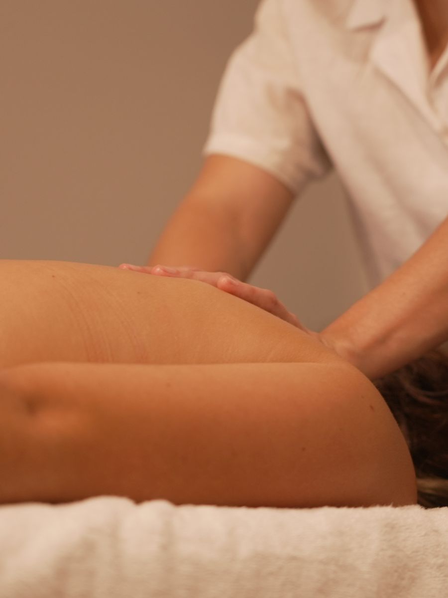 Close view of a therapist's hands working across a client's shoulder