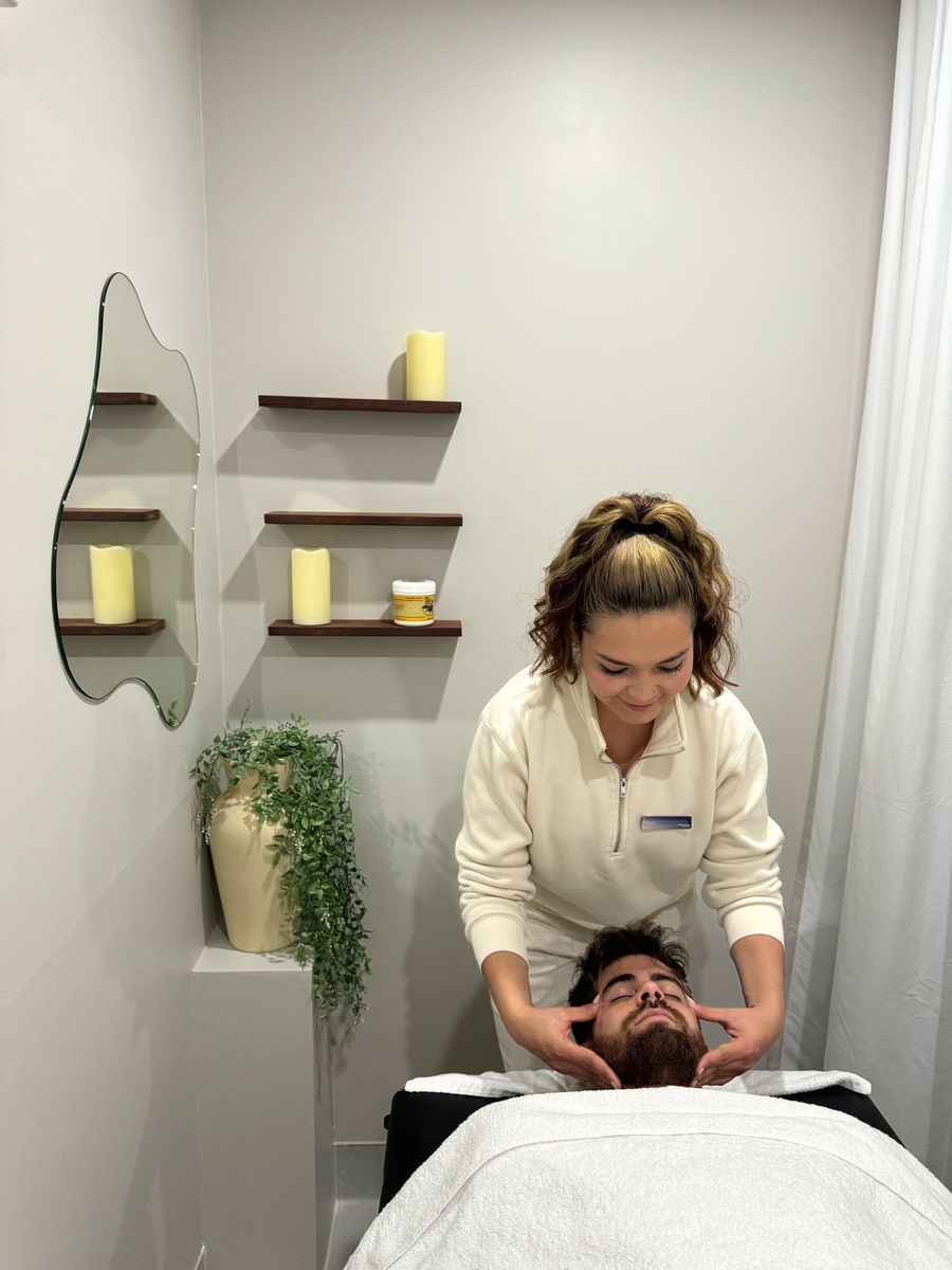 The massage room at Renew, with a shaped mirror, candles on timber shelves and a plant beside the table