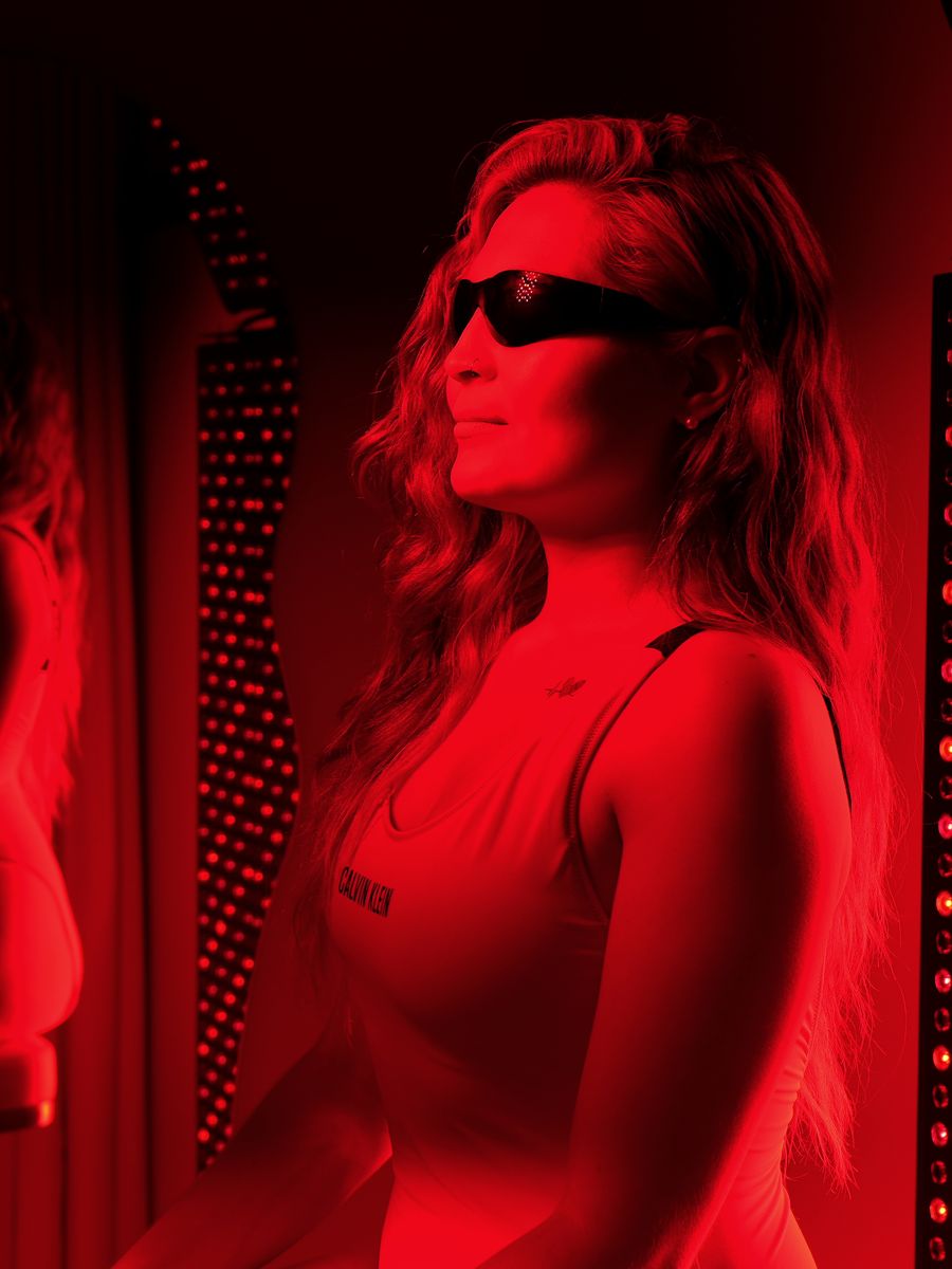 Two people sitting in front of the red light therapy panels at Renew