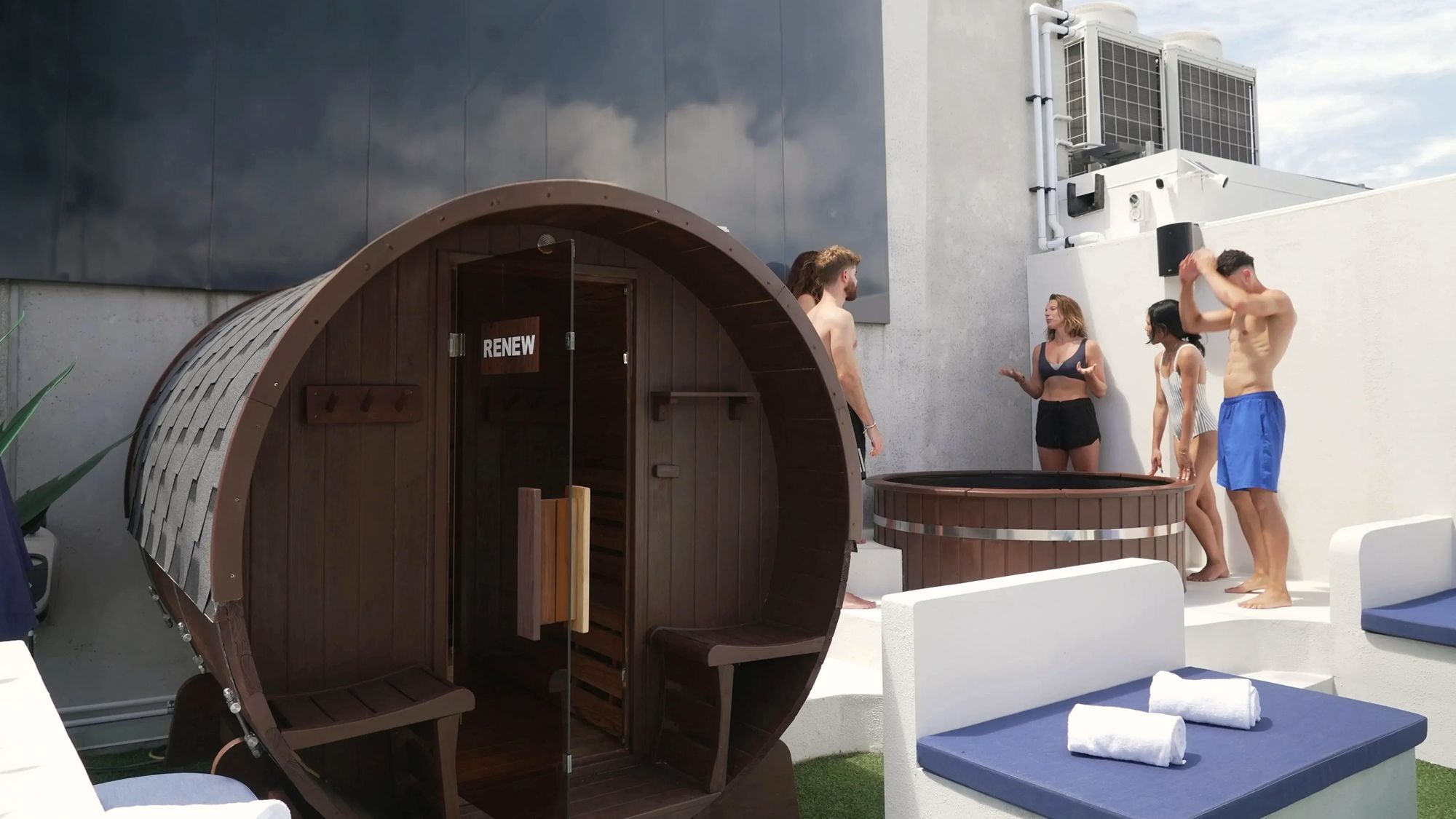 The barrel sauna and ice bath on the rooftop at Renew, with a group standing around them