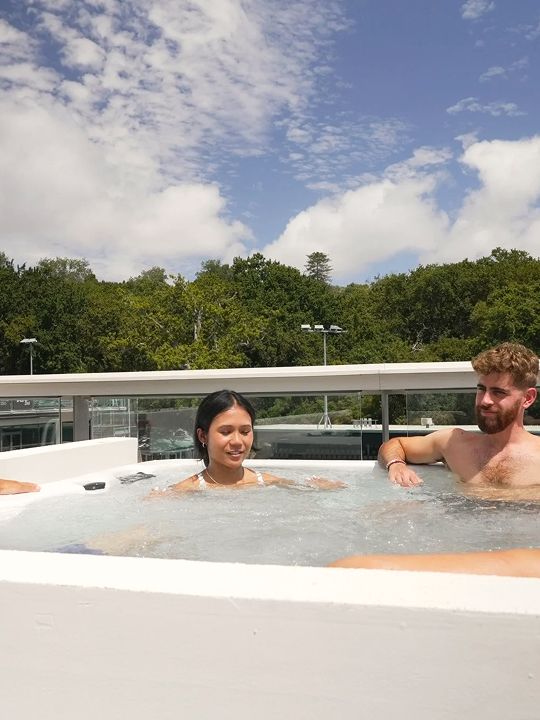 People in the spa bath on the Renew rooftop, with trees and sky behind